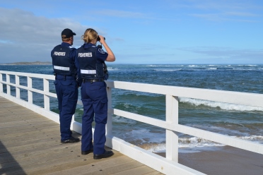 A male and female fisheries officer standing on a wharf looking out to sea.